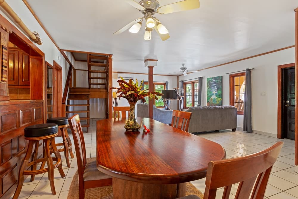 An open-concept living space with a wooden dining table and chairs in the foreground, leading to a living room area with a sofa and armchairs.