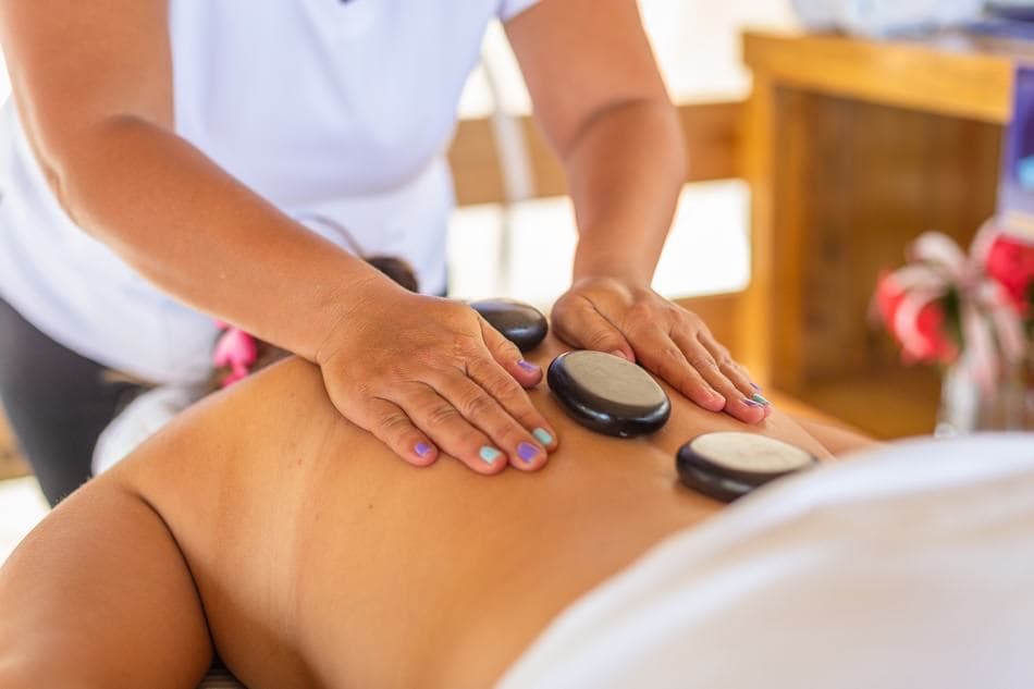 A massage therapist applies hot stones to a client's back.