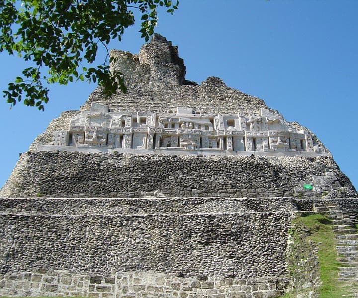 Mayan pyramid with ornate carvings against a clear blue sky.