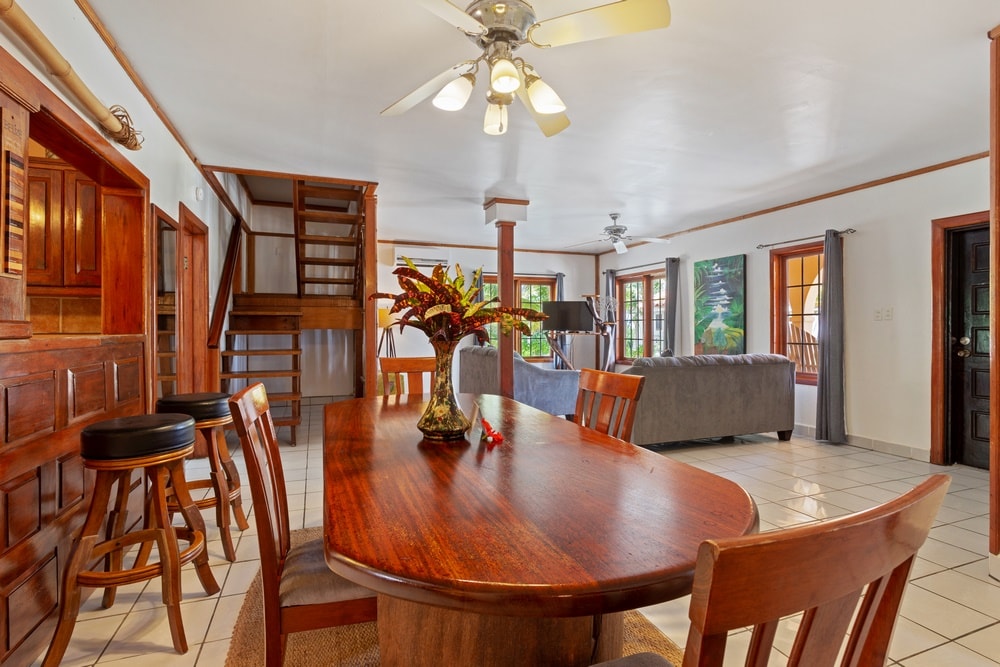 An open-concept living space with a wooden dining table and chairs in the foreground, leading to a living room area with a sofa and armchairs.