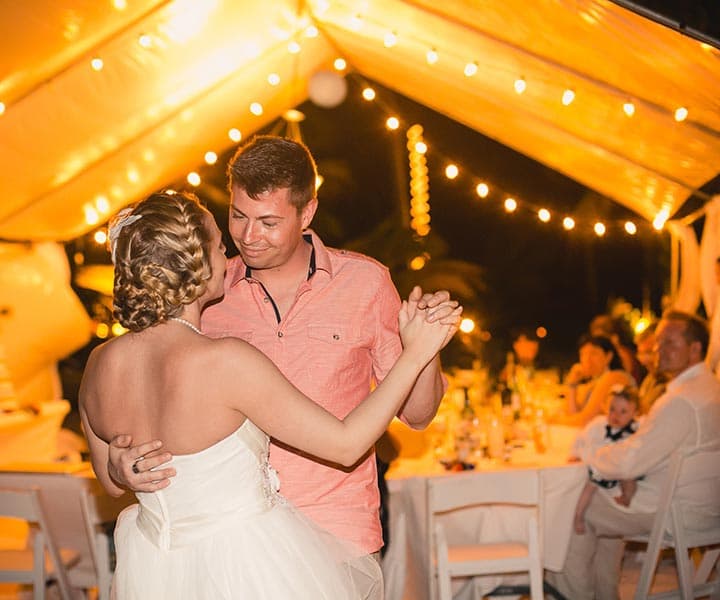 A couple dances together under warm lights at a wedding reception.