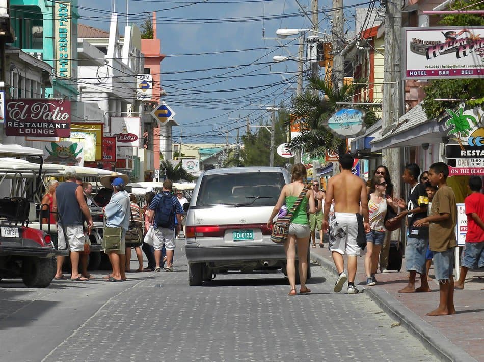 Busy street scene with pedestrians, vehicles, and colorful storefronts under a clear sky.